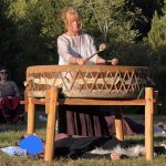 Gudrun spielt die große Mother-Drum auf einem Holzgestell